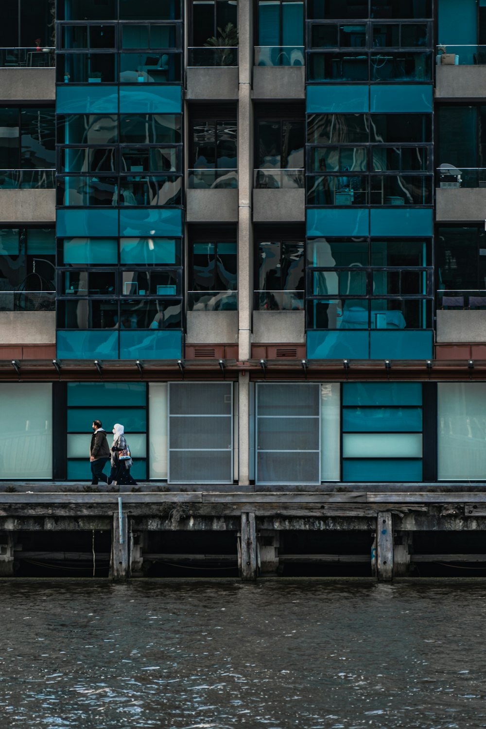 um casal de pessoas em pé em uma doca em frente a um prédio