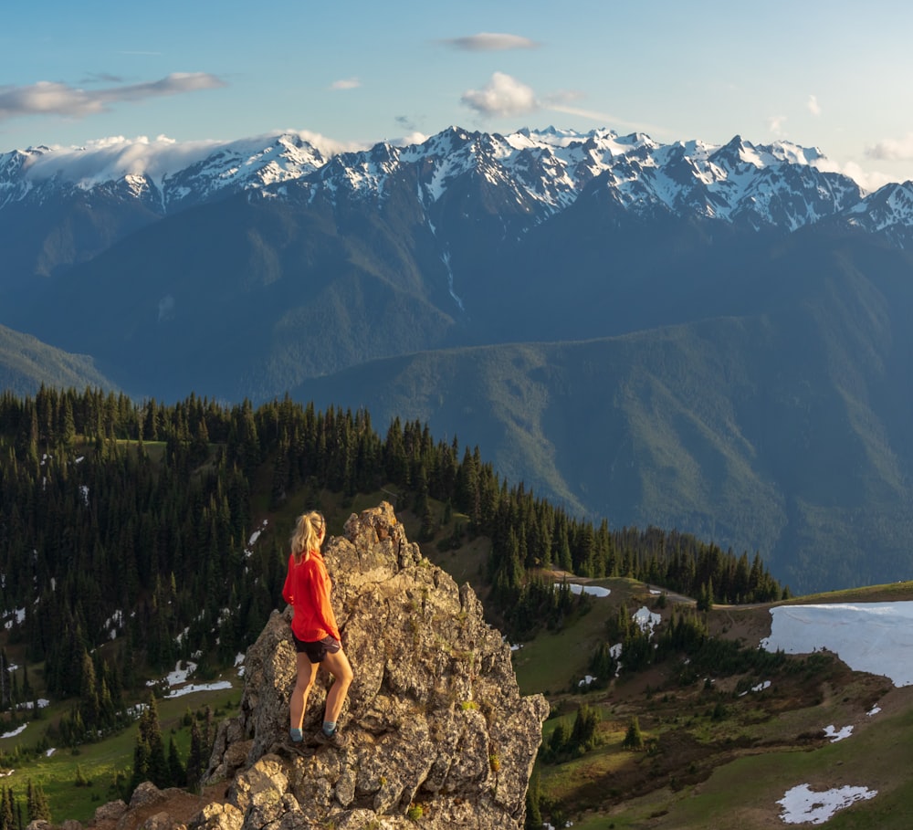 a man standing on a rock overlooking a lake and mountains