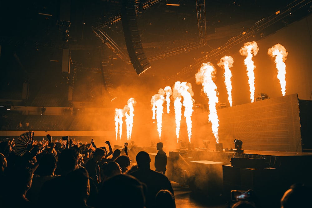 a group of people watching a stage with fire and smoke