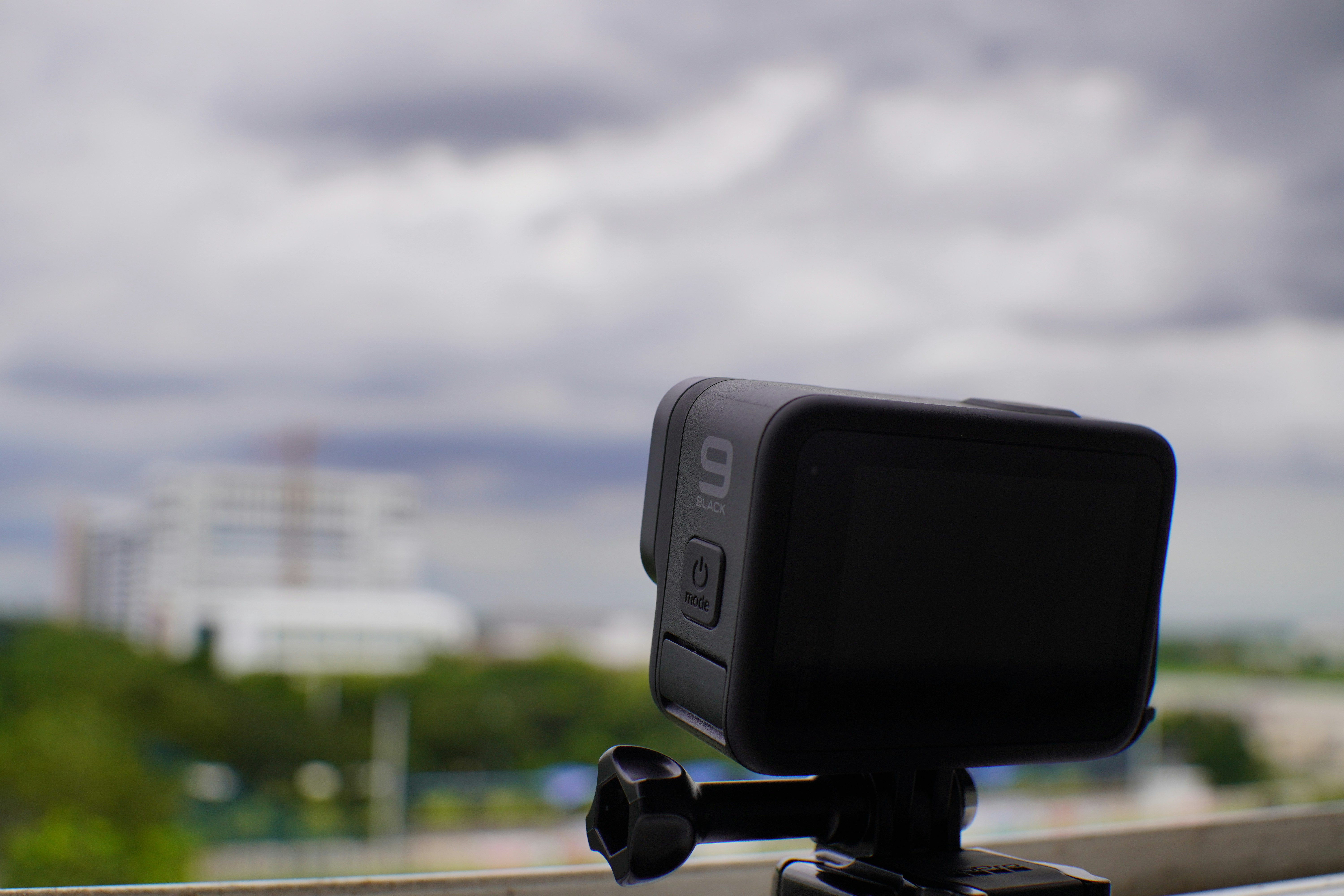 Black dash camera mounted on windshield, bright daytime highway road visible through glass