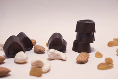 Variety of chocolate pieces with nuts and dried fruits on a marble surface.