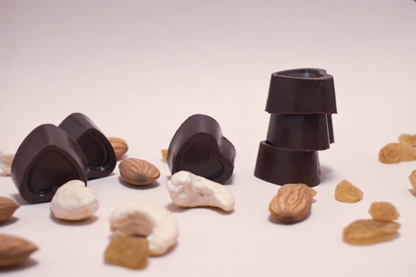 An overhead shot of a simple snack plate with mixed nuts, dried apricots, and dark chocolate squares.