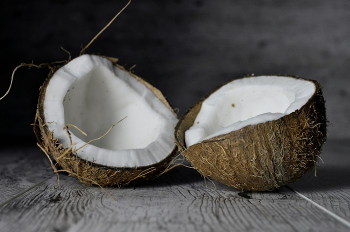 Halved coconuts on dark wood