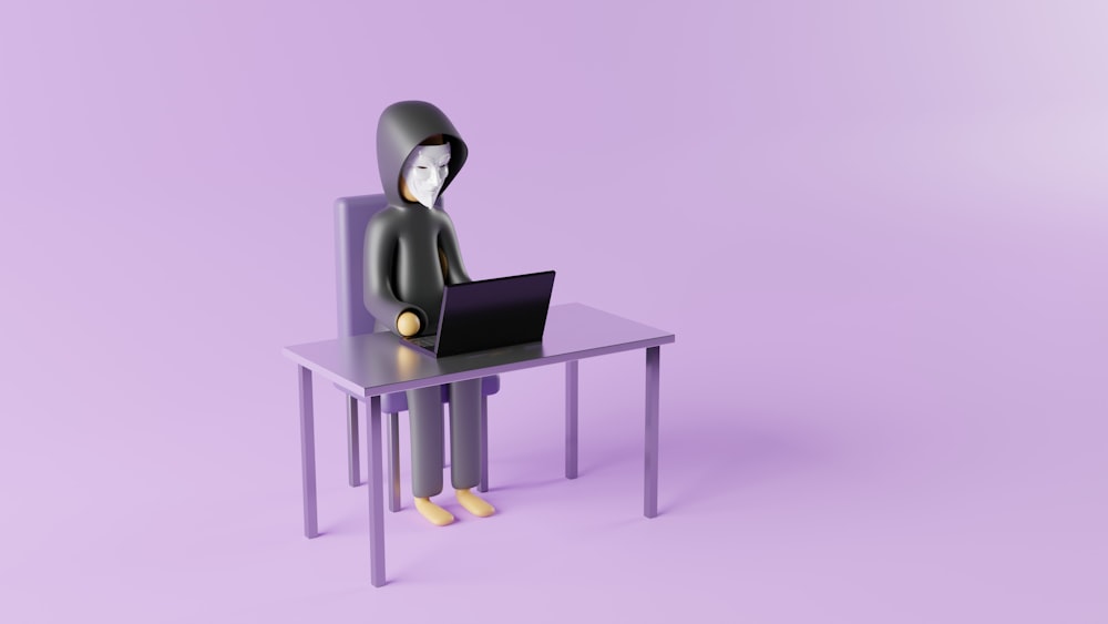 une personne assise à un bureau avec un ordinateur portable dessus