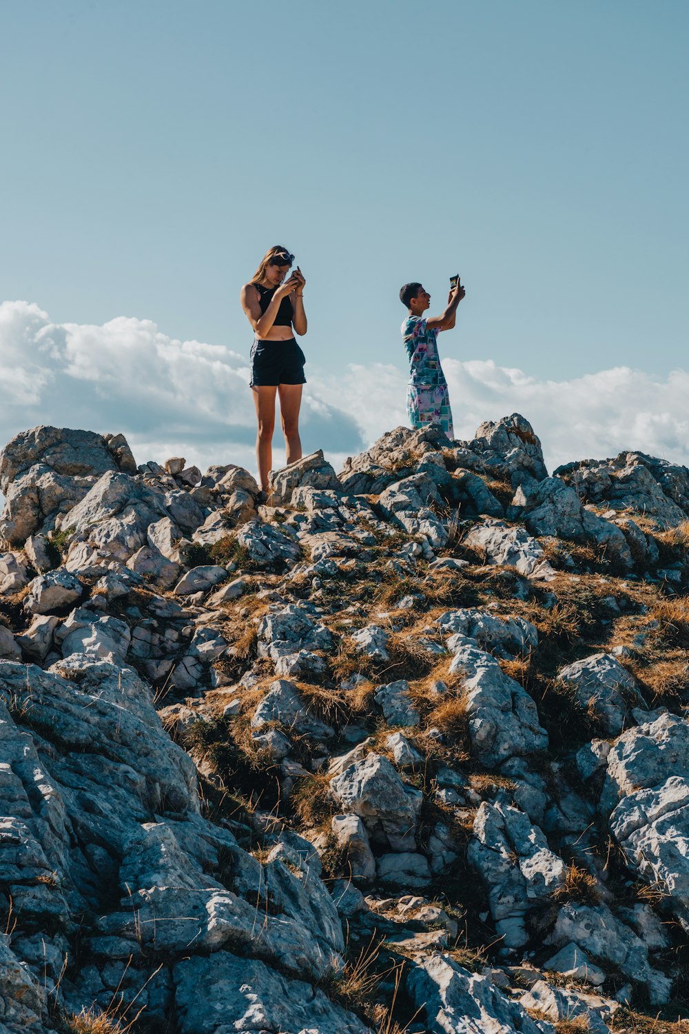 um homem e uma mulher de pé em uma colina rochosa