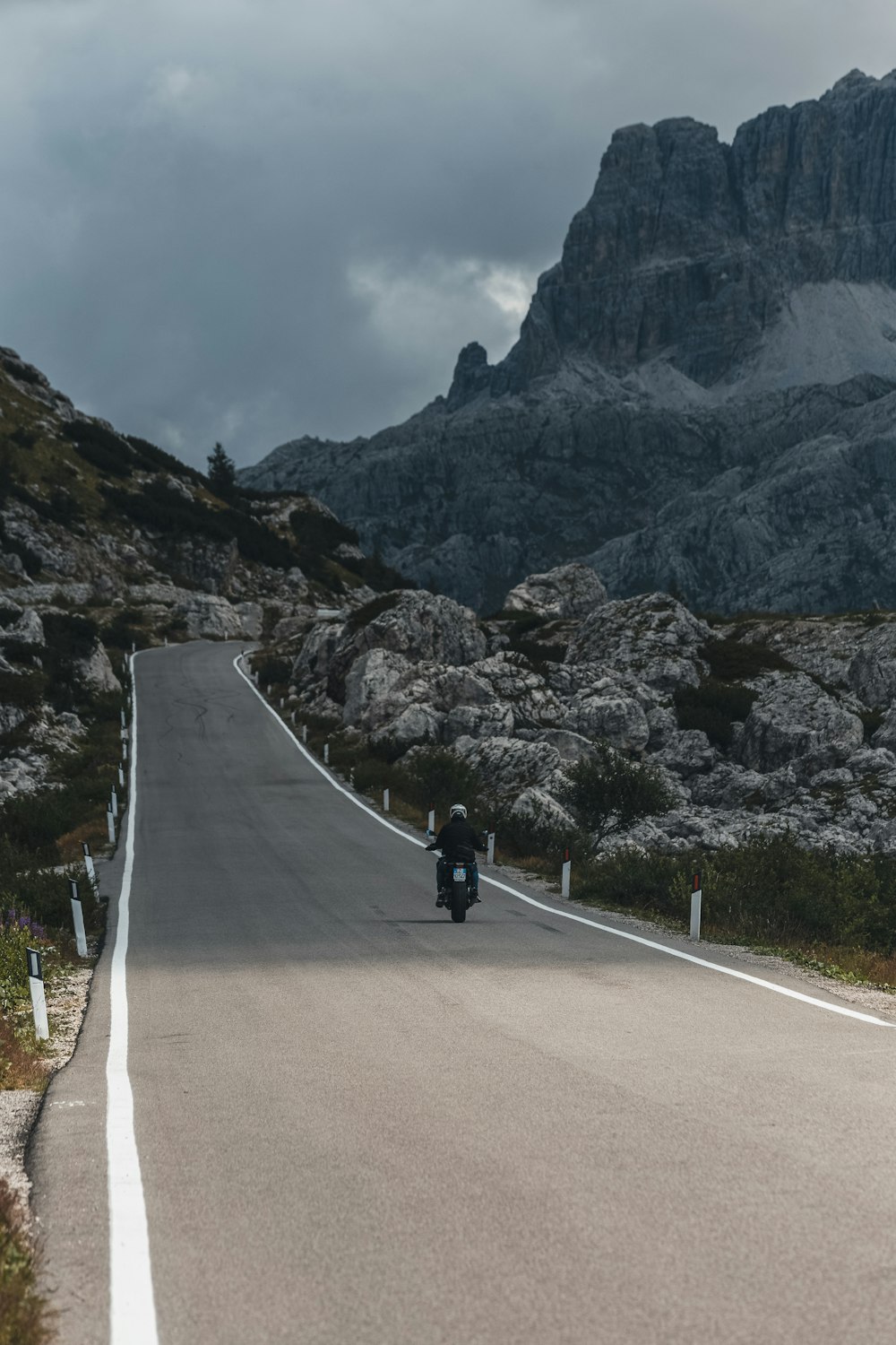 a person riding a motorcycle on a road between mountains