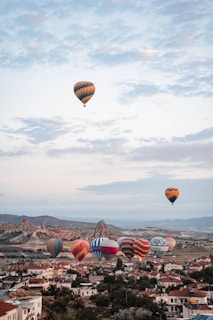Colorful hot air balloons floating over a green valley.