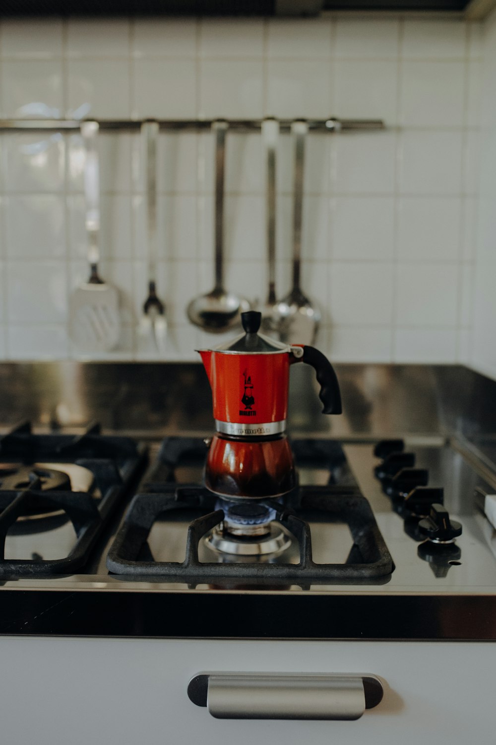 a red and silver tea kettle on a stove
