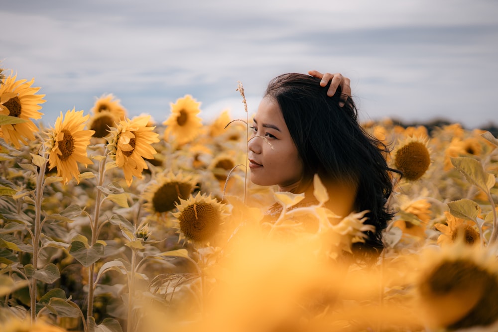 Eine Frau liegt in einem Sonnenblumenfeld