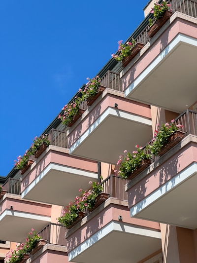 Modern sleek metal planters arranged neatly along a balcony railing with blooming flowers.