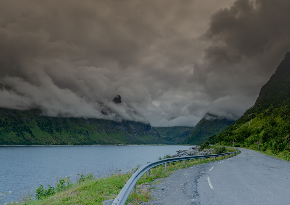 a road next to a body of water with mountains in the background