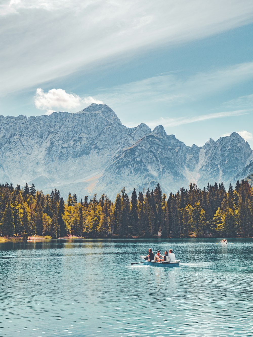 um grupo de pessoas em um barco em um lago com montanhas ao fundo