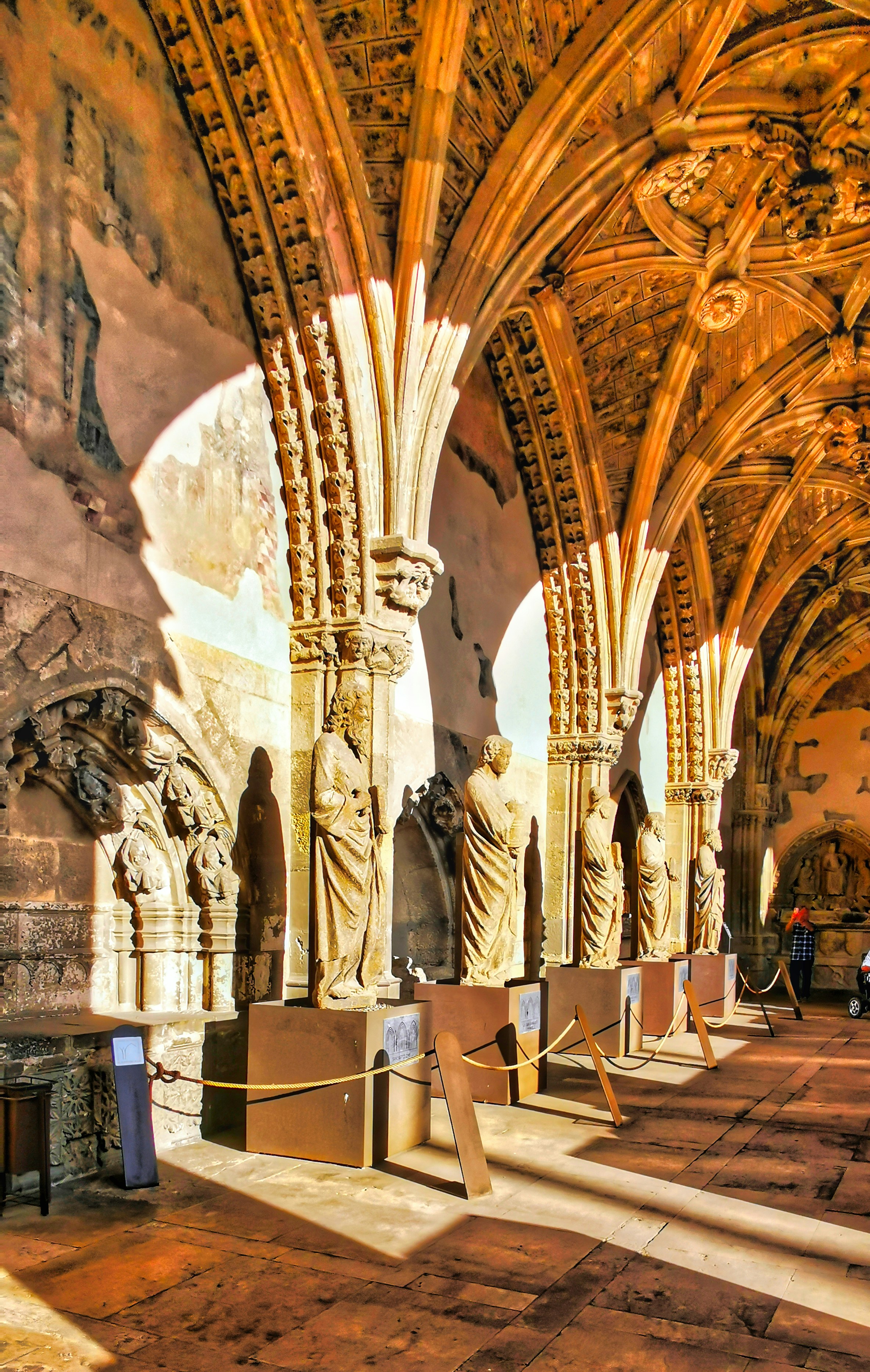 Bright, airy ancient stone corridor with warm natural light, open and well-lit scholarly setting