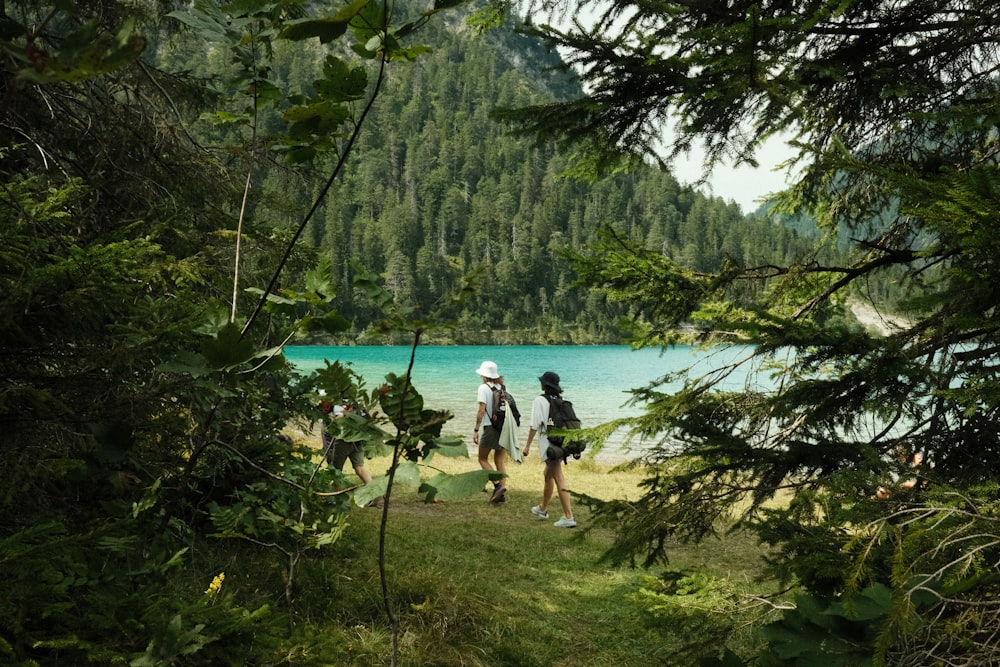 a couple of people walking on a path by a lake