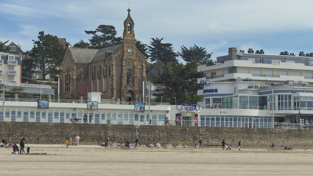 a group of people on a beach, Une balade sur la plage Val-André avec vue sur la Chapelle et le Casino.