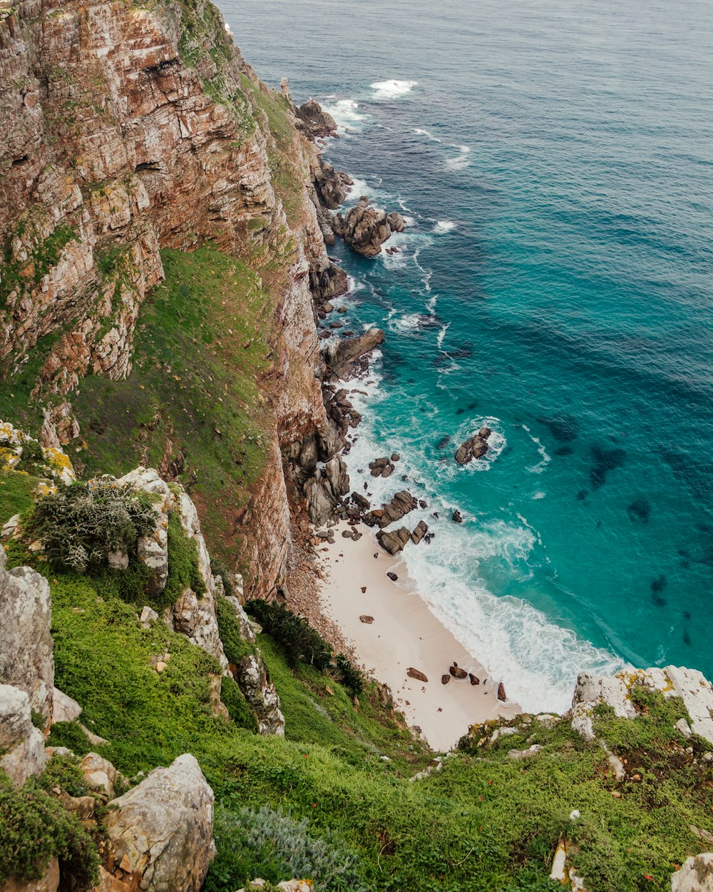 a rocky beach with a body of water in the background