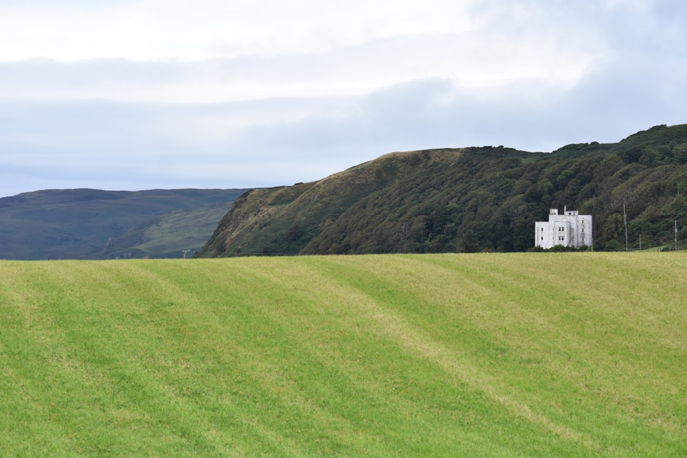 a grassy field with a white building in the distance