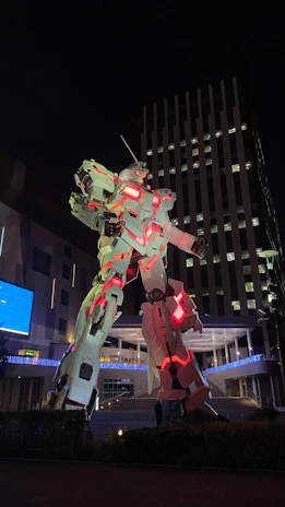 A sleek silver robot with glowing blue eyes standing against a neon-lit cityscape.