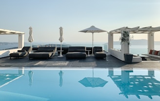 a pool with lounge chairs and umbrellas by it
