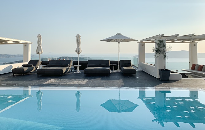 a pool with lounge chairs and umbrellas by it