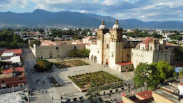 a large building with a dome and a courtyard with people walking around