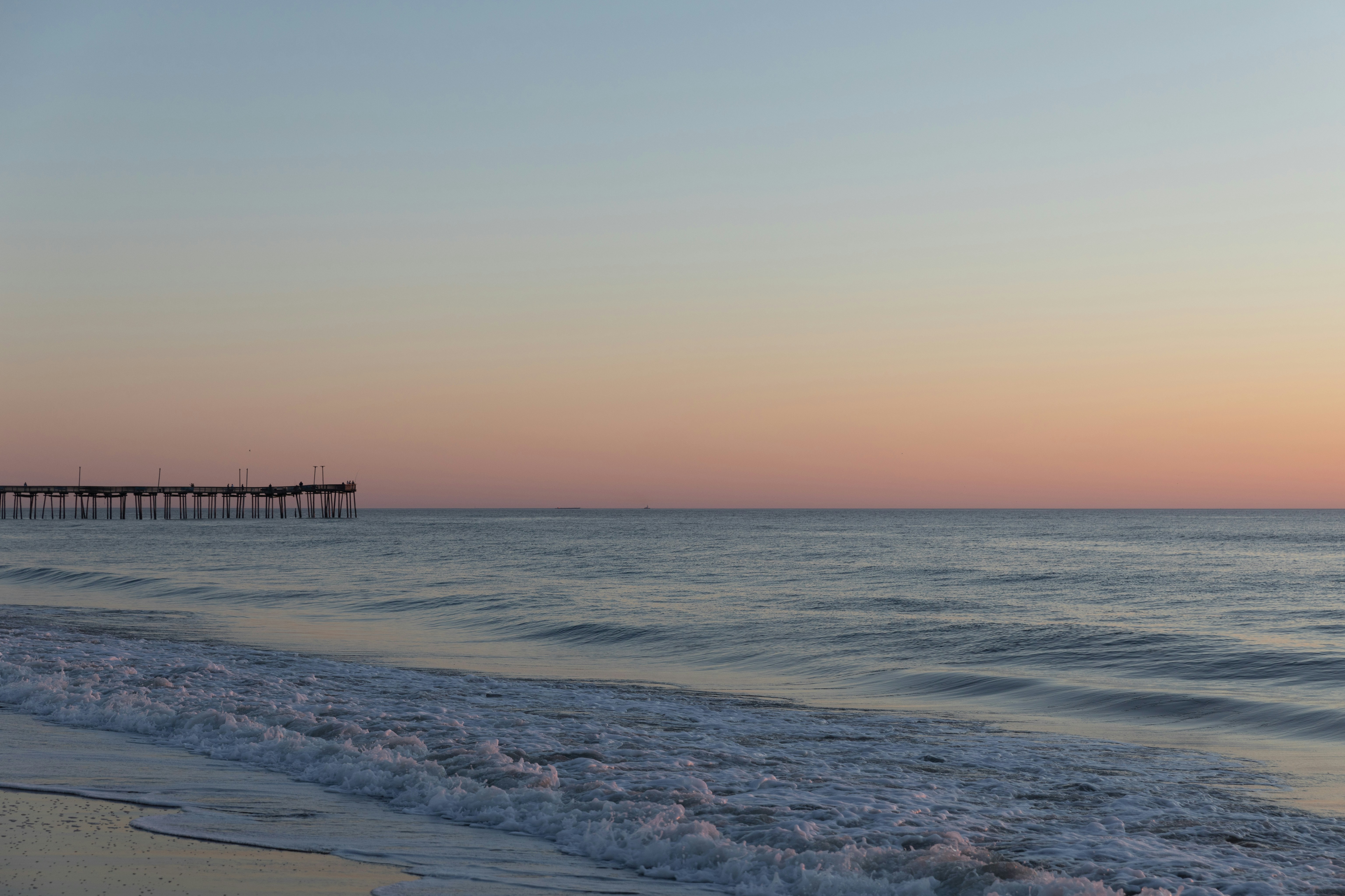 a beach with a pier in the distance