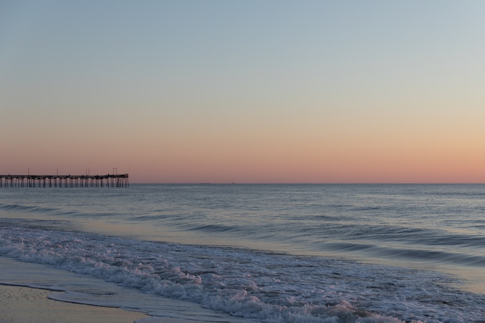 a beach with a pier in the distance