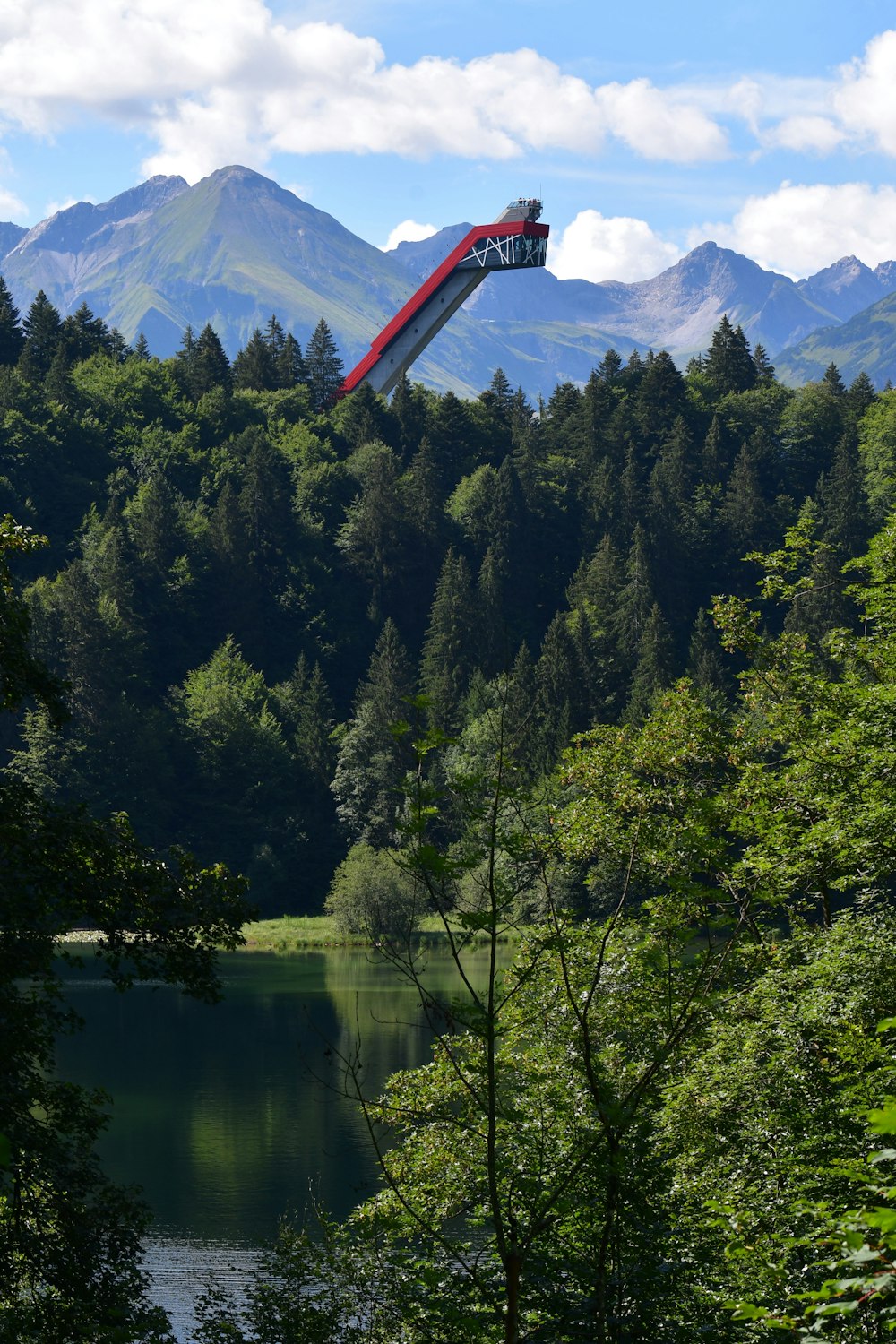 a red and white parachute over a river surrounded by trees and mountains