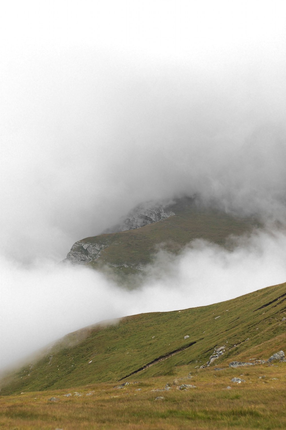 a grassy hill with a foggy sky above