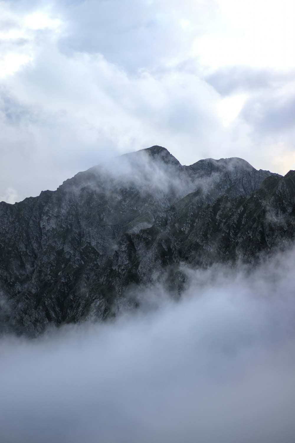 a mountain with clouds below