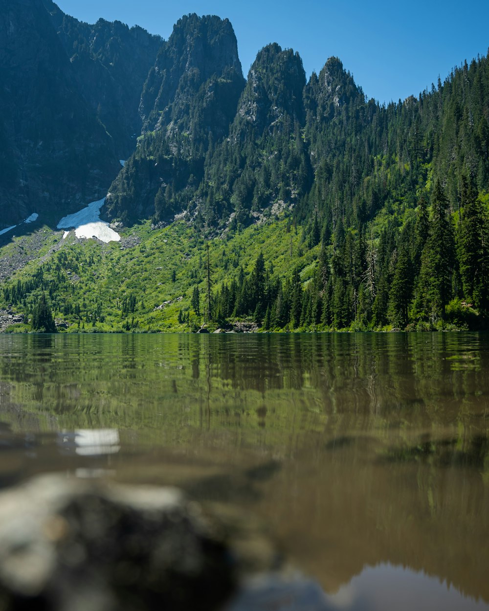 a lake with trees and mountains in the background