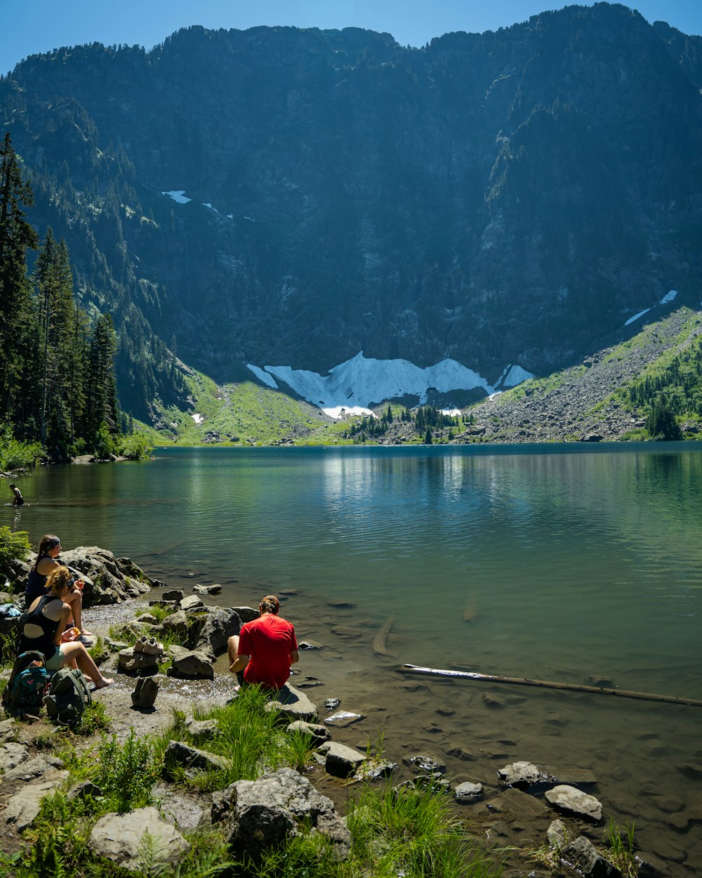 pessoas sentadas em rochas à beira de um lago
