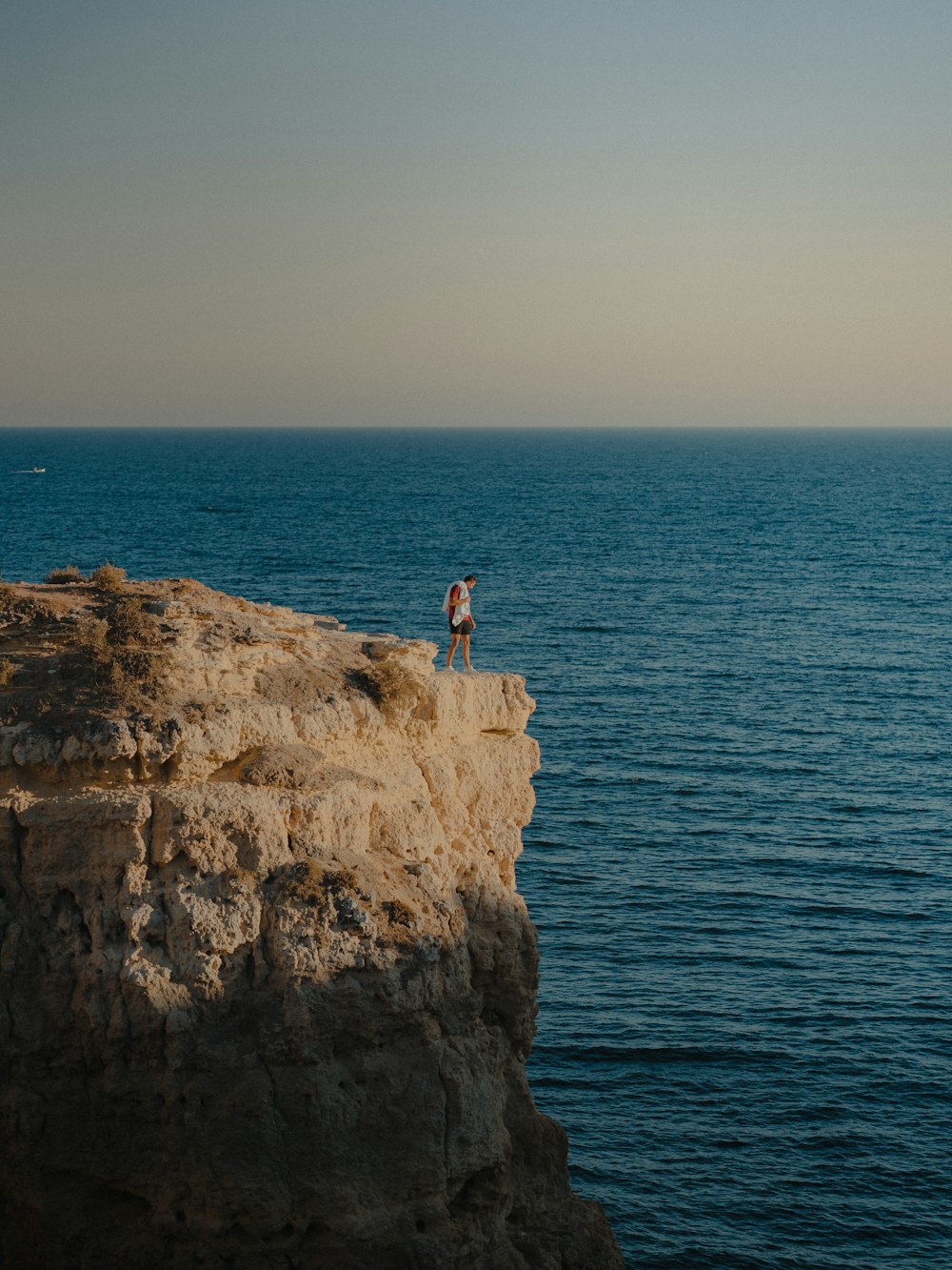 a person standing on a cliff above the ocean