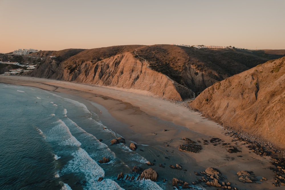 a beach with a body of water and rocky cliffs