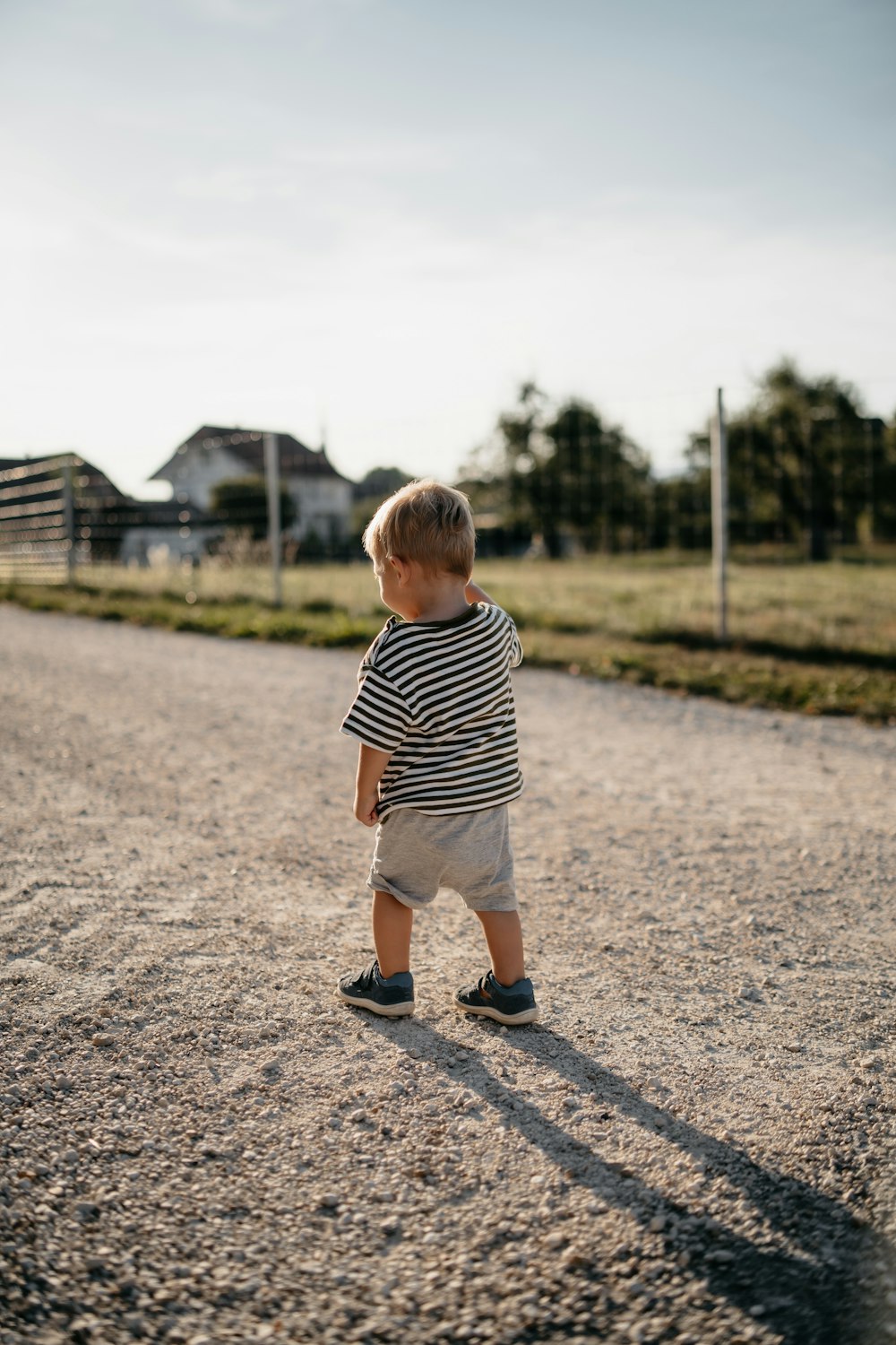 a boy standing on a gravel road