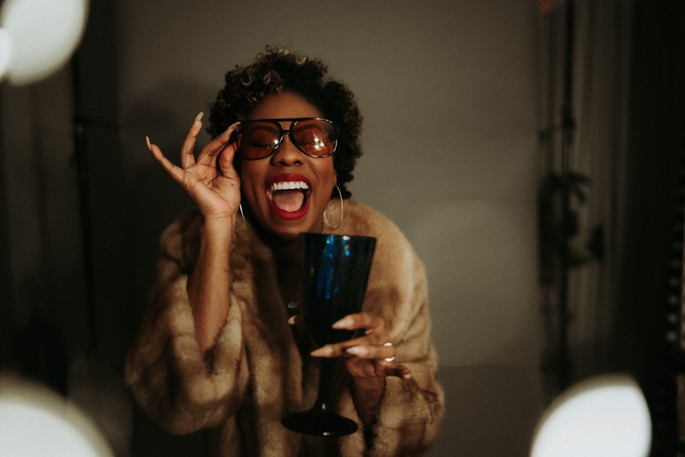 a person with curly hair and glasses holding a microphone