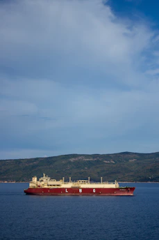 A close-up of a large LNG vessel docked for maintenance under a clear blue sky.