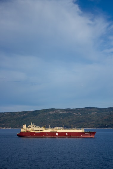 A close-up of a large LNG vessel docked for maintenance under a clear blue sky.