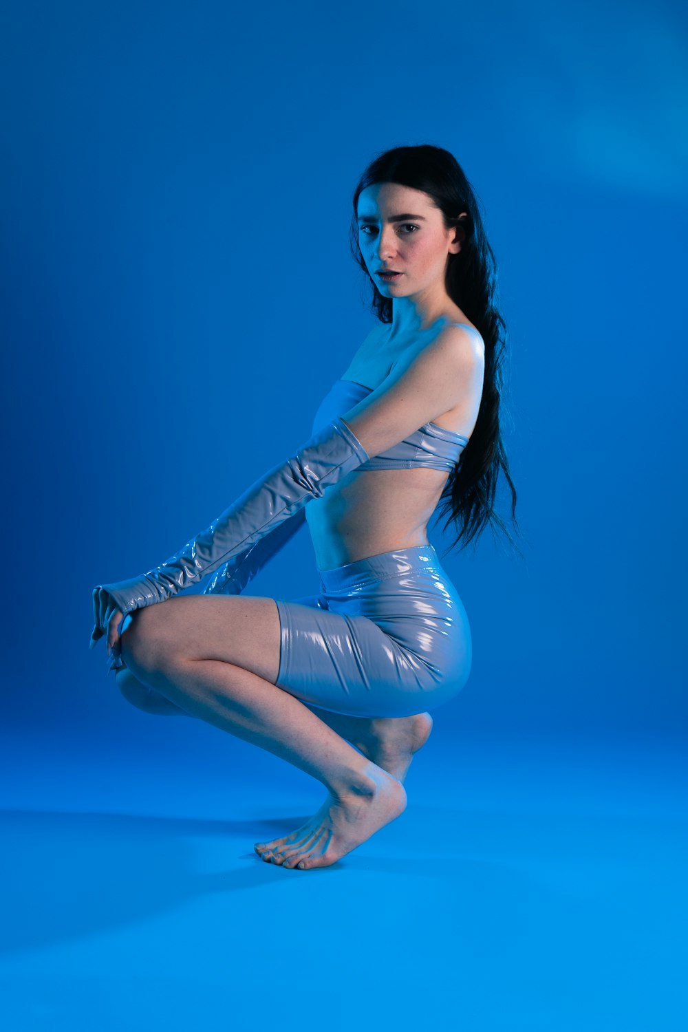 uma mulher em um vestido azul de pé ao lado de um corpo de água