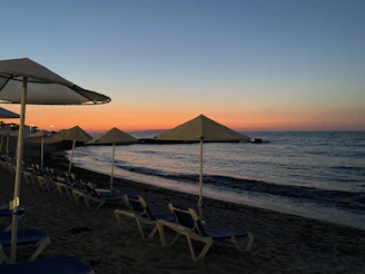 Sunset view over the calm Mediterranean sea with beach loungers and umbrellas