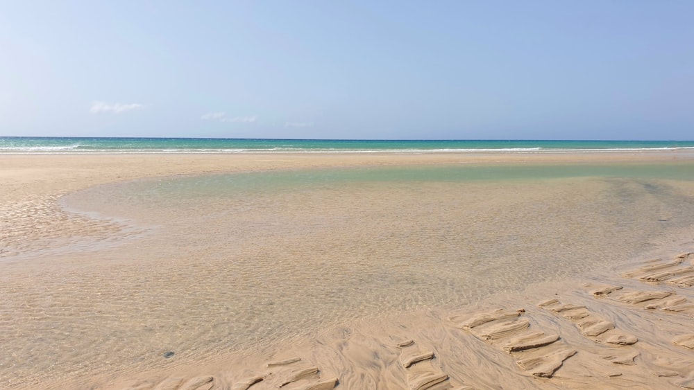 a sandy beach with blue sky and water