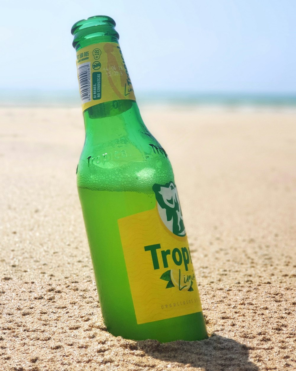 a green bottle on a beach