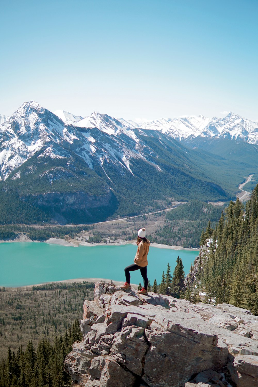 a person standing on a rock overlooking a lake and mountains