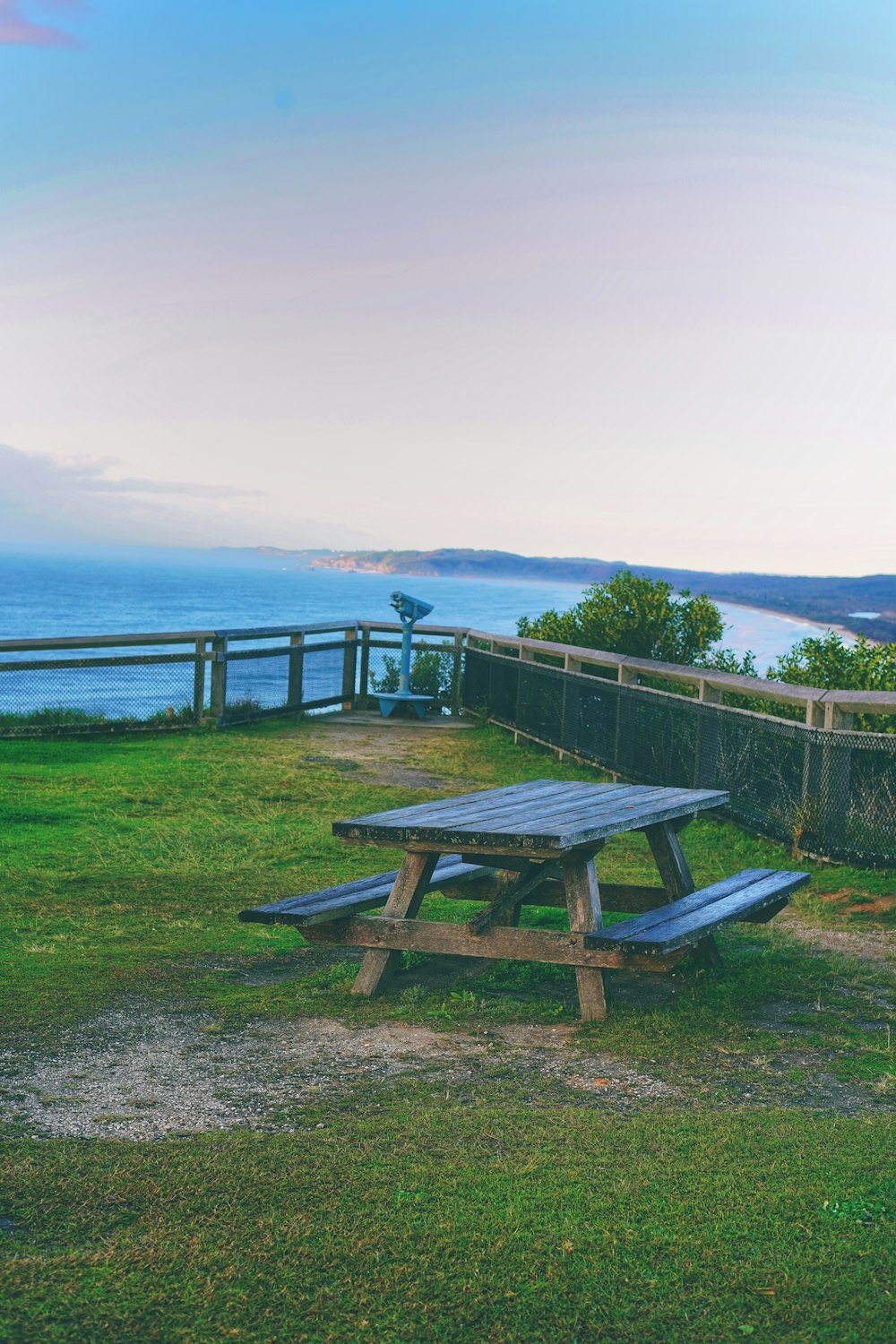 a picnic table on a grassy hill overlooking a body of water