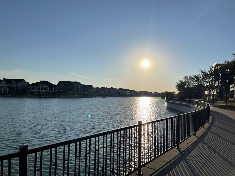 a body of water with a railing and buildings in the background