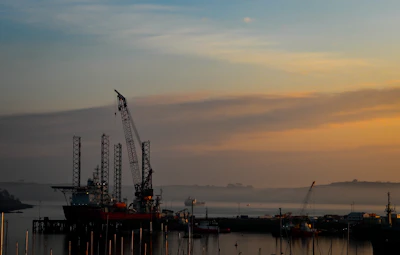 A skilled marine engineer inspecting a complex offshore drilling rig at sunset.