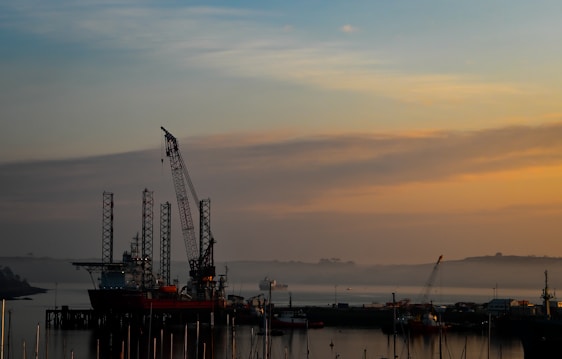 Support vessel navigating offshore waters at sunset near oil rigs.