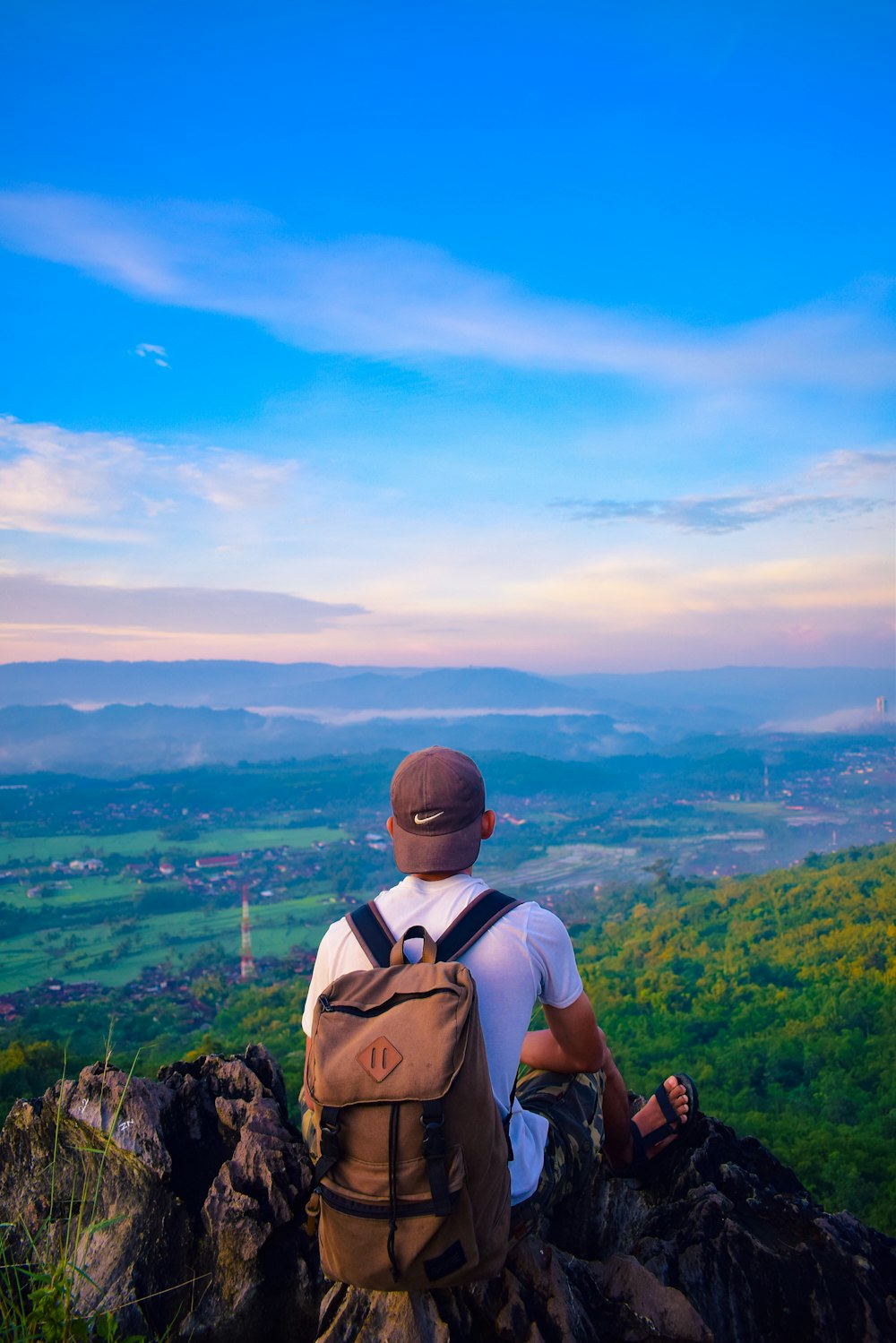 a man sitting on a rock overlooking a valley