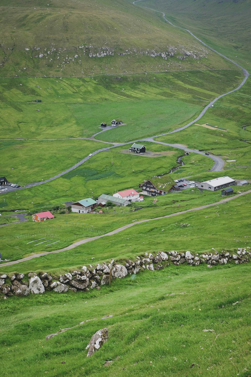 a green landscape with houses and cars