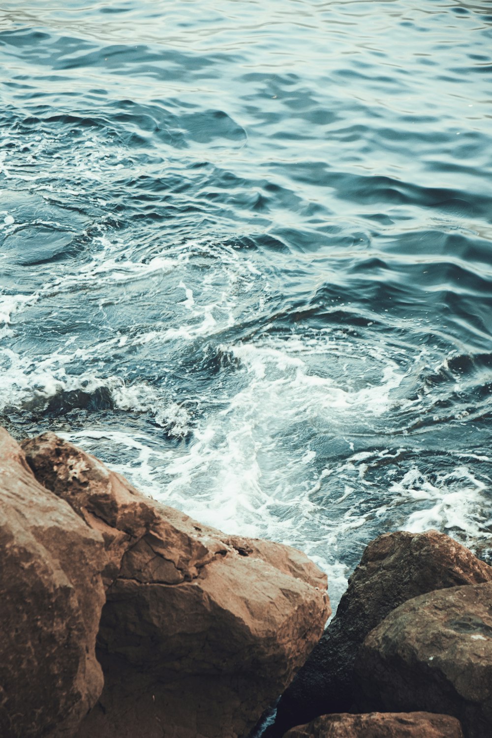 uno specchio d'acqua con rocce e onde che si infrangono su di esso